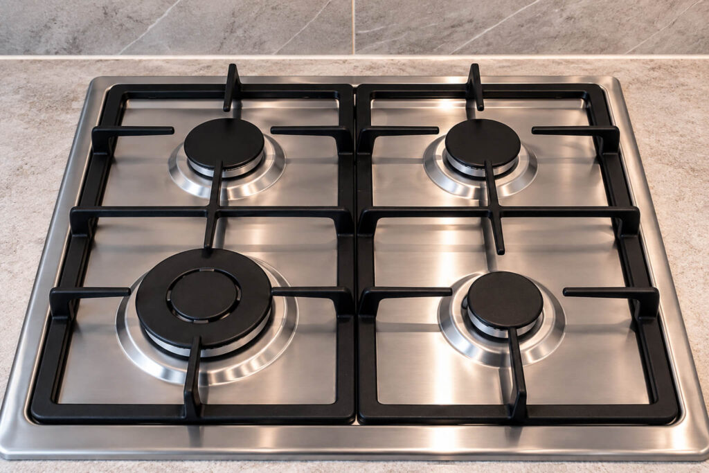 Gas hob after professional cleaning with clean burners and polished stainless steel surface