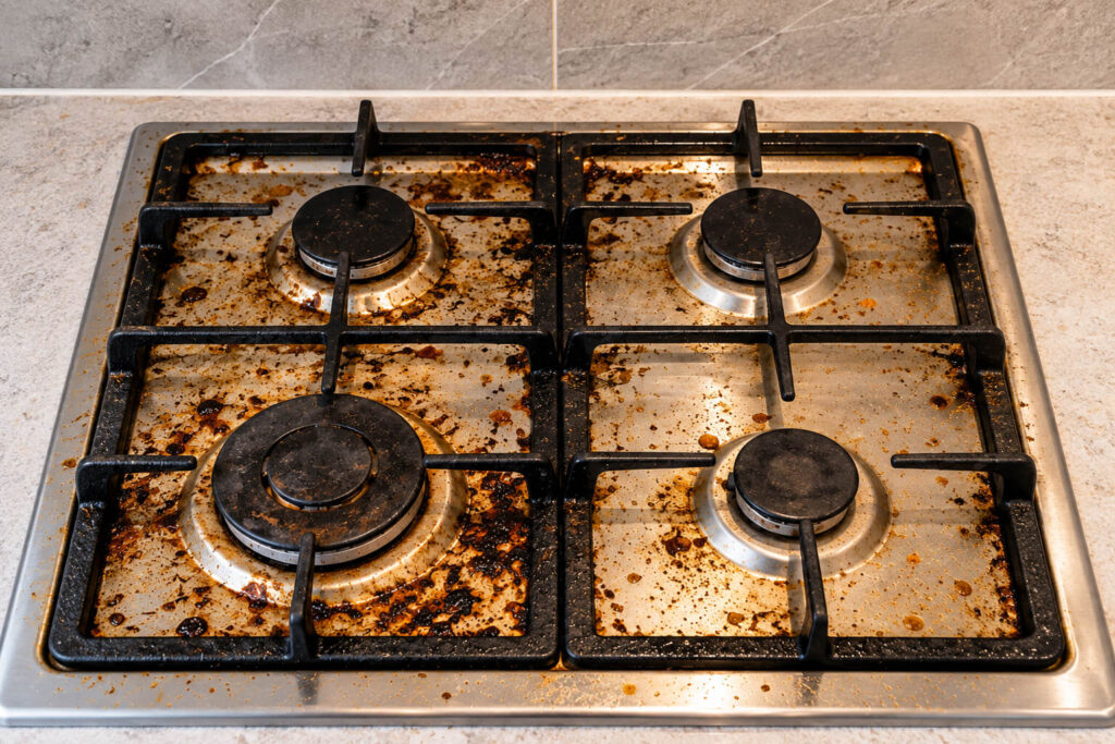 Gas hob before professional cleaning with grease and burnt-on food residue